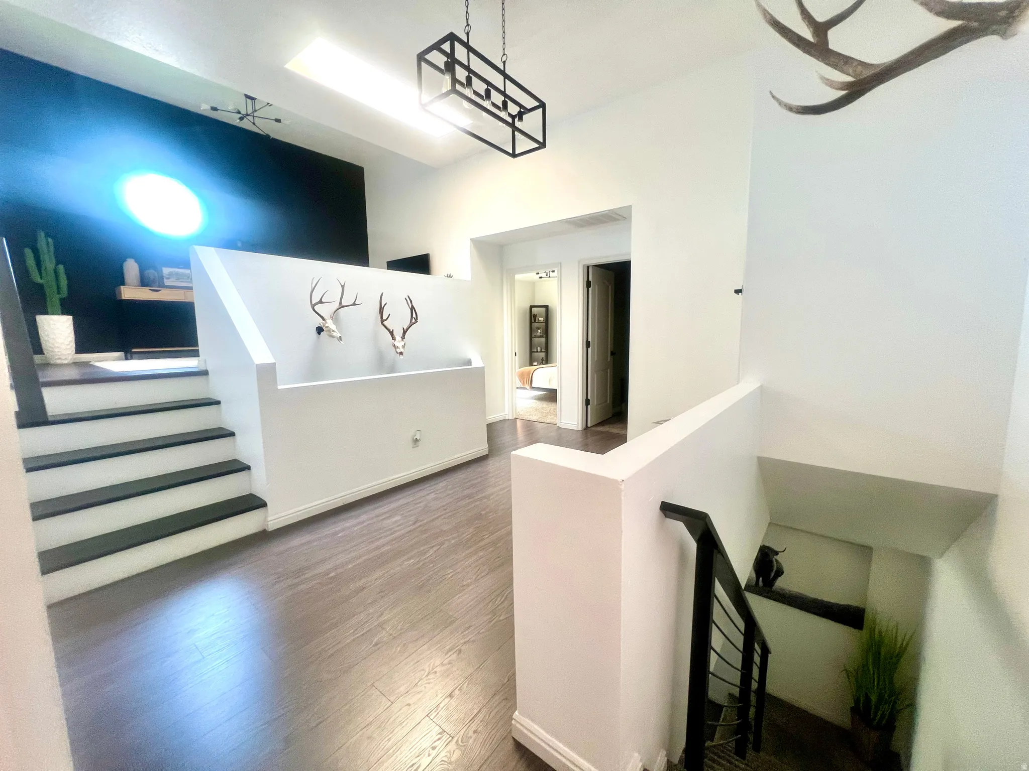Upper-level landing featuring wood-finish flooring, a skylight, and a contemporary linear chandelier