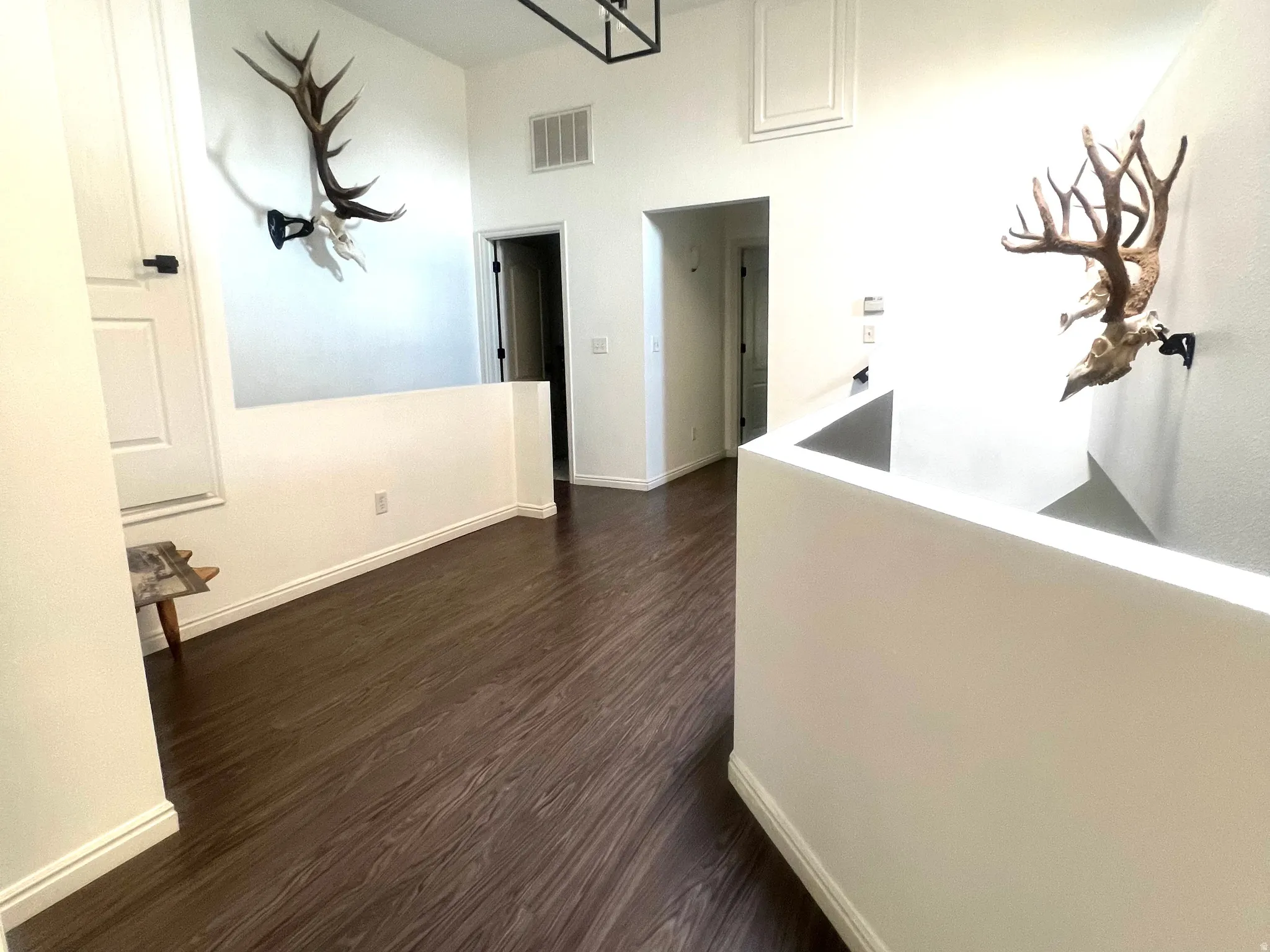 Upper-level hallway featuring dark wood-finish flooring, white walls, and a recessed ceiling panel