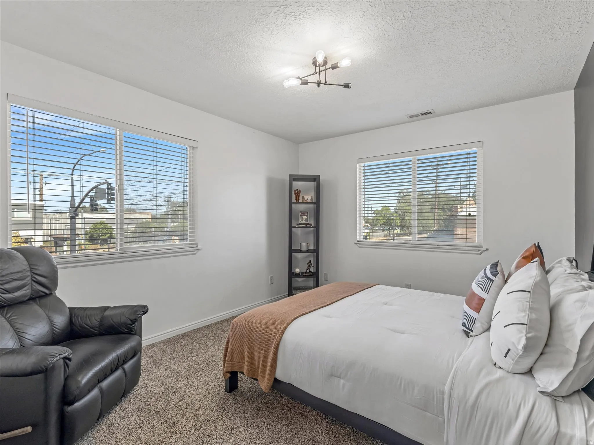 Carpeted room featuring two windows with horizontal blinds, a modern ceiling light fixture, and white painted walls