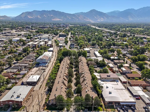 Aerial perspective showcasing a residential development with rows of attached housing units, each featuring a brown shingle roof