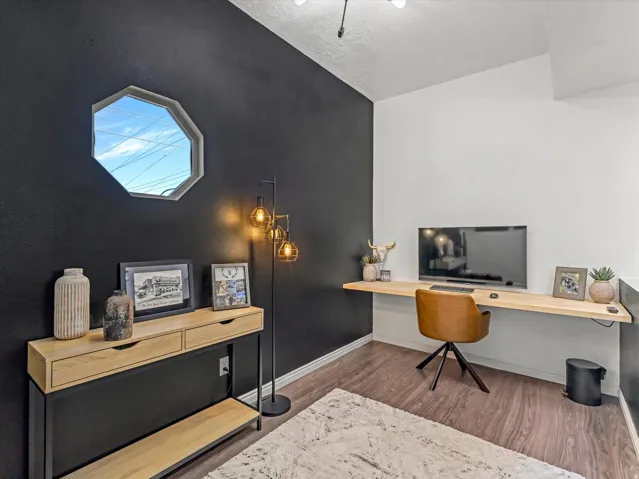 Dedicated workspace featuring a floating wood-finish desk and wood-finish flooring