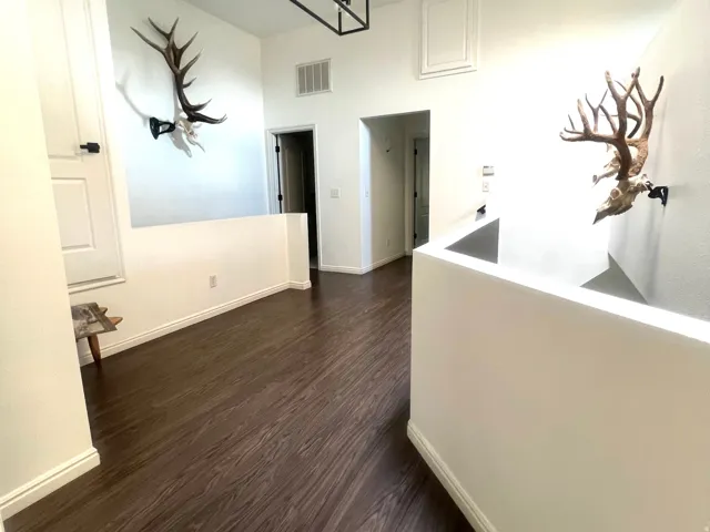 Upper-level hallway featuring dark wood-finish flooring, white walls, and a recessed ceiling panel