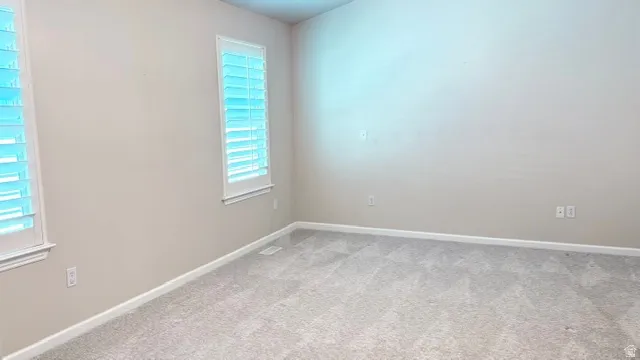 Neutral-toned room featuring a vaulted ceiling and textured carpeting