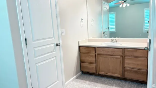 Bathroom vanity featuring light wood-finish cabinetry with multiple drawers, an integrated sink, and a light-toned countertop