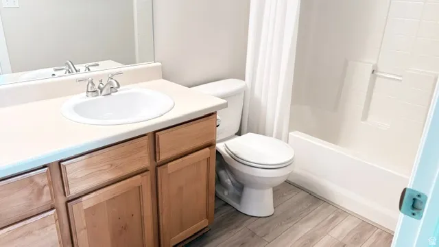 Bathroom featuring a single basin vanity with wood-finish cabinetry, a toilet, and a bathtub with an integrated shower