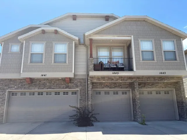 Multi-level townhouse exterior featuring stacked stone accents, horizontal siding, and textured shake siding