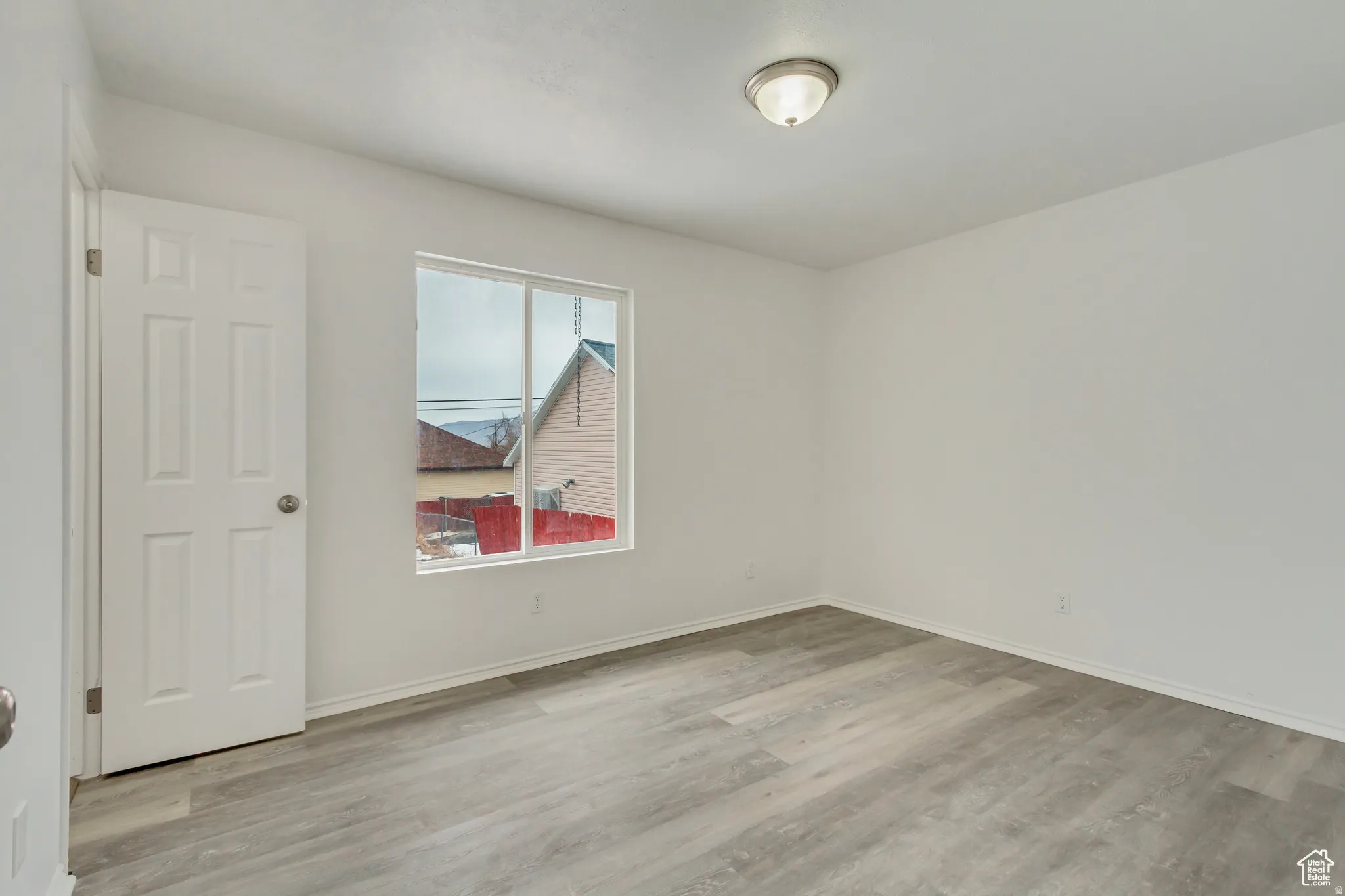 Room featuring light gray wood-finish flooring, white painted walls, and a window with white trim
