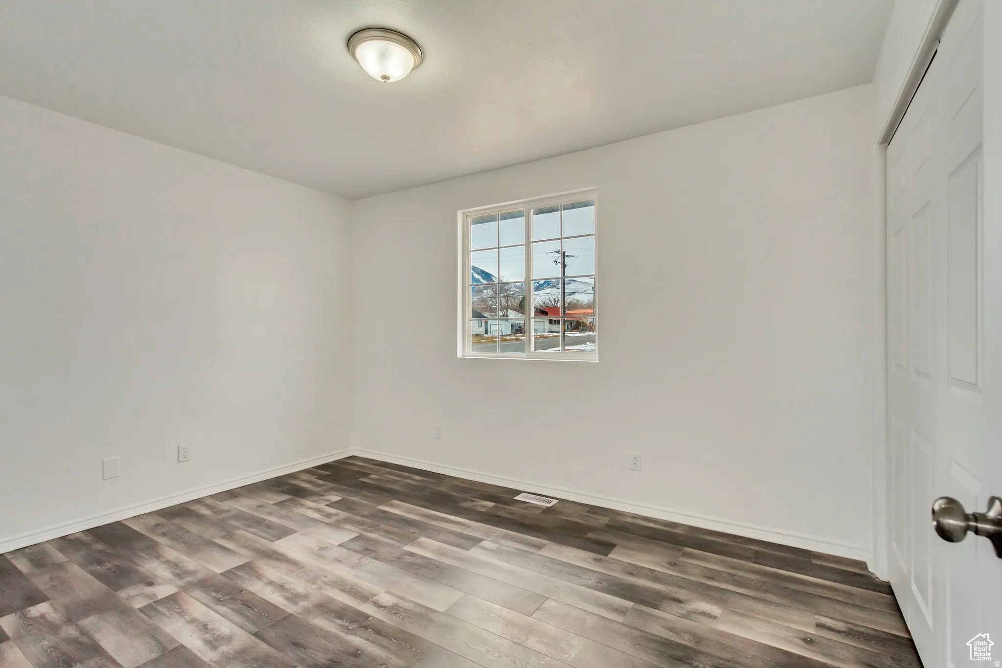 Room featuring wood-finish flooring, white walls, and a window with mountain backdrop