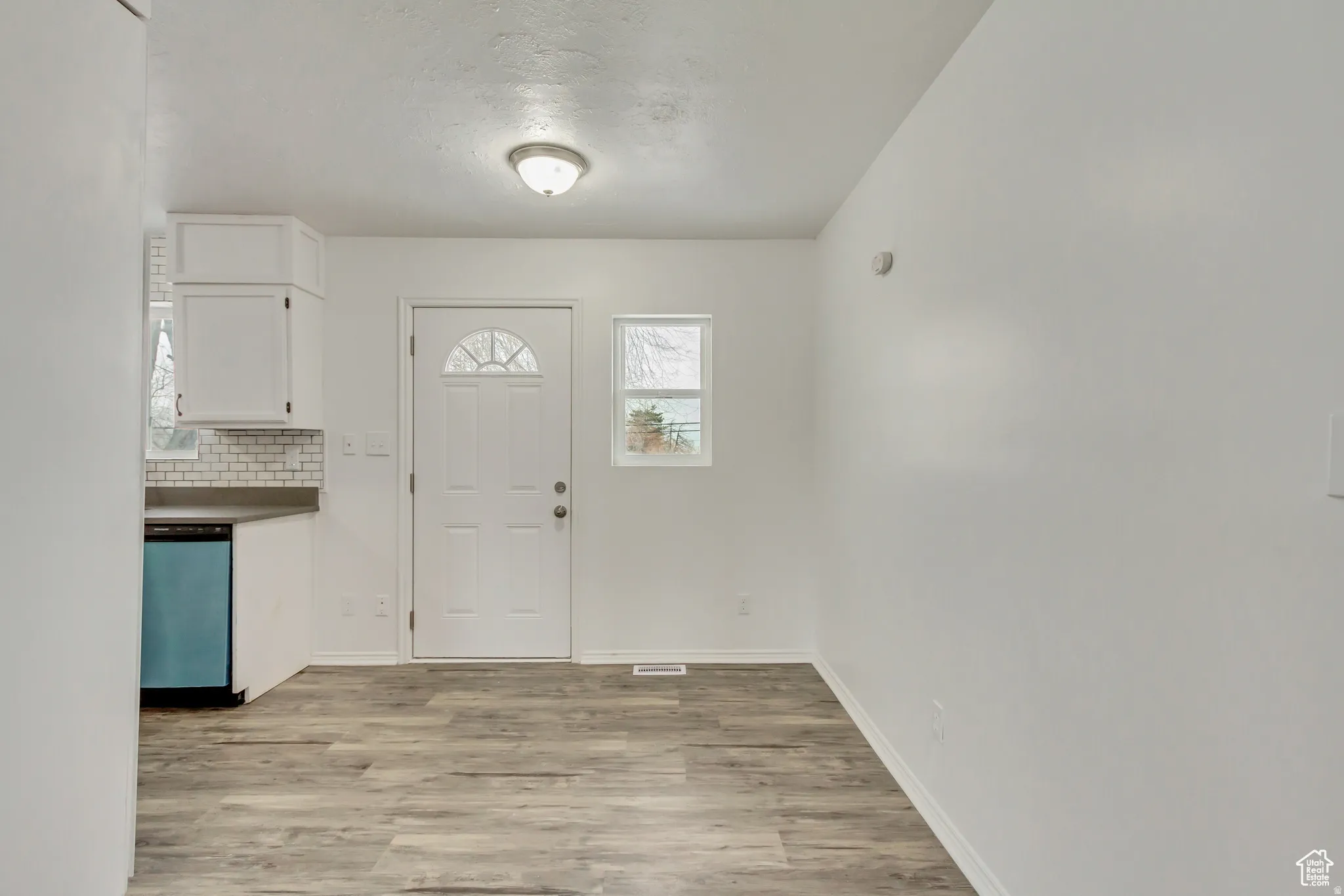 Entry area featuring wood-finish flooring, white walls, and a paneled door with an arched window insert