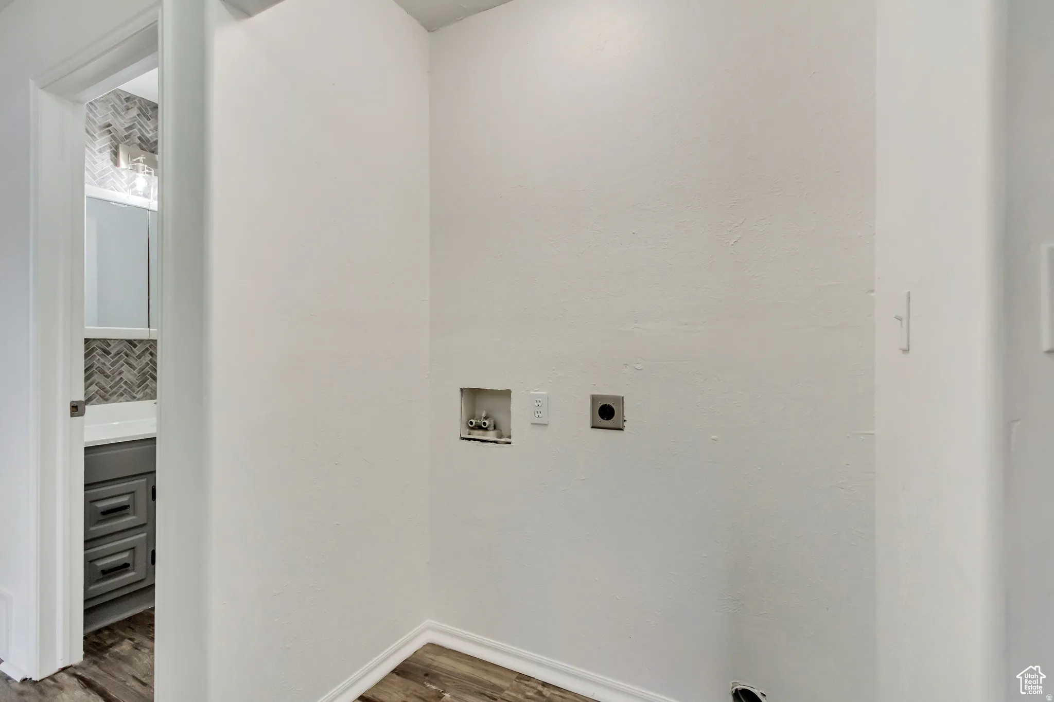Dedicated laundry area with utility hookups and wood-finish flooring