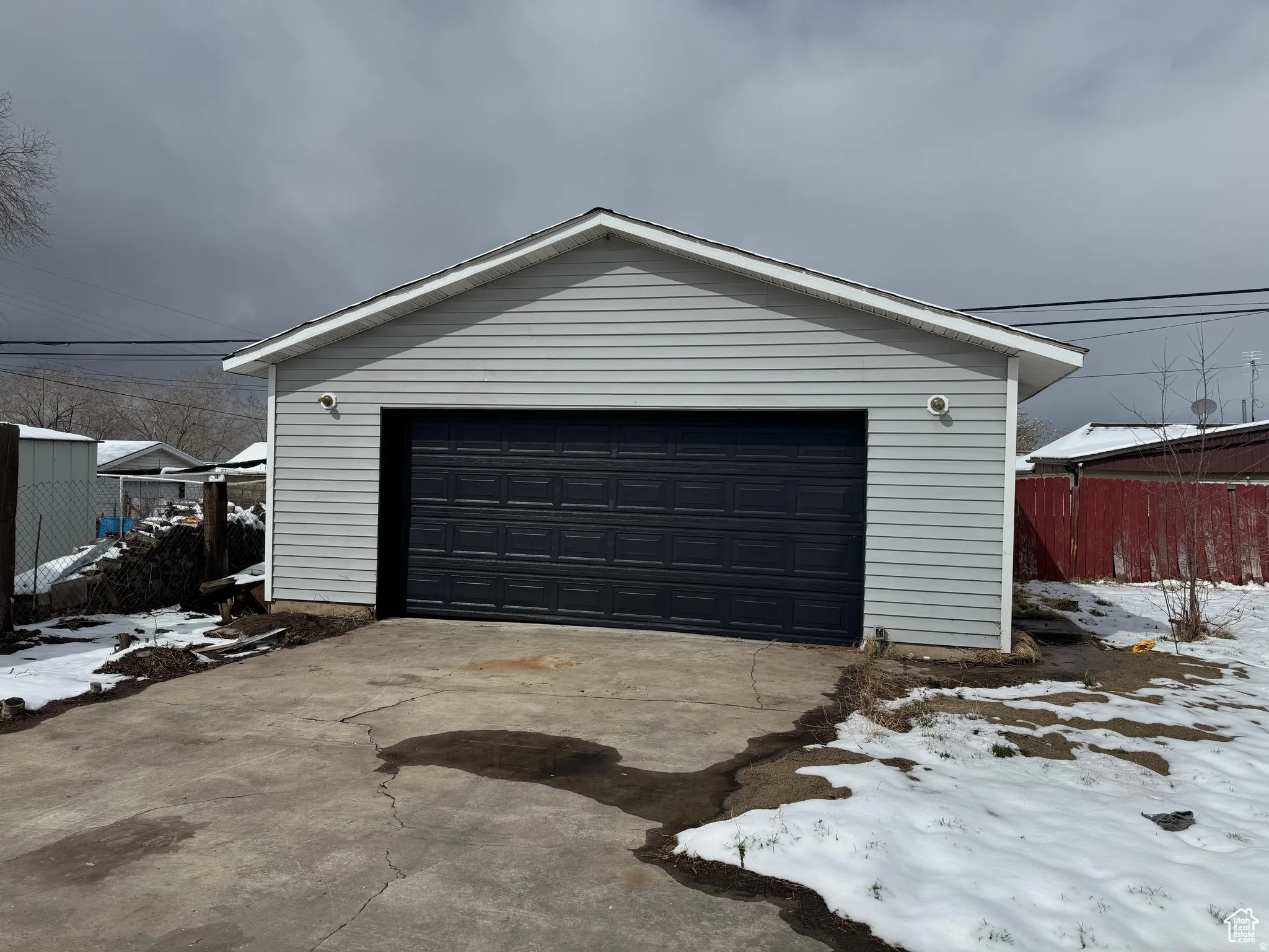 Detached garage with light gray siding and a dark gray panel garage door