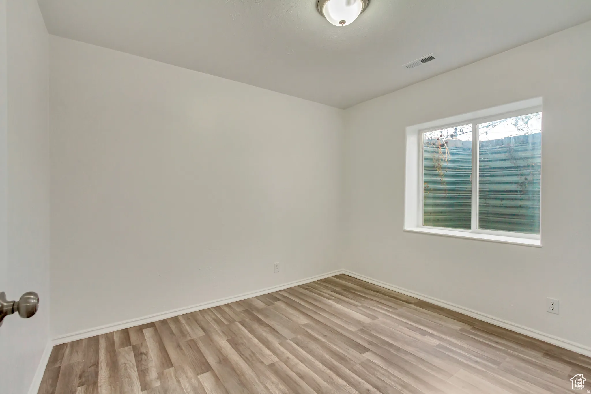 Neutral white walls, wood-finish flooring, white trim, and a window with a sill