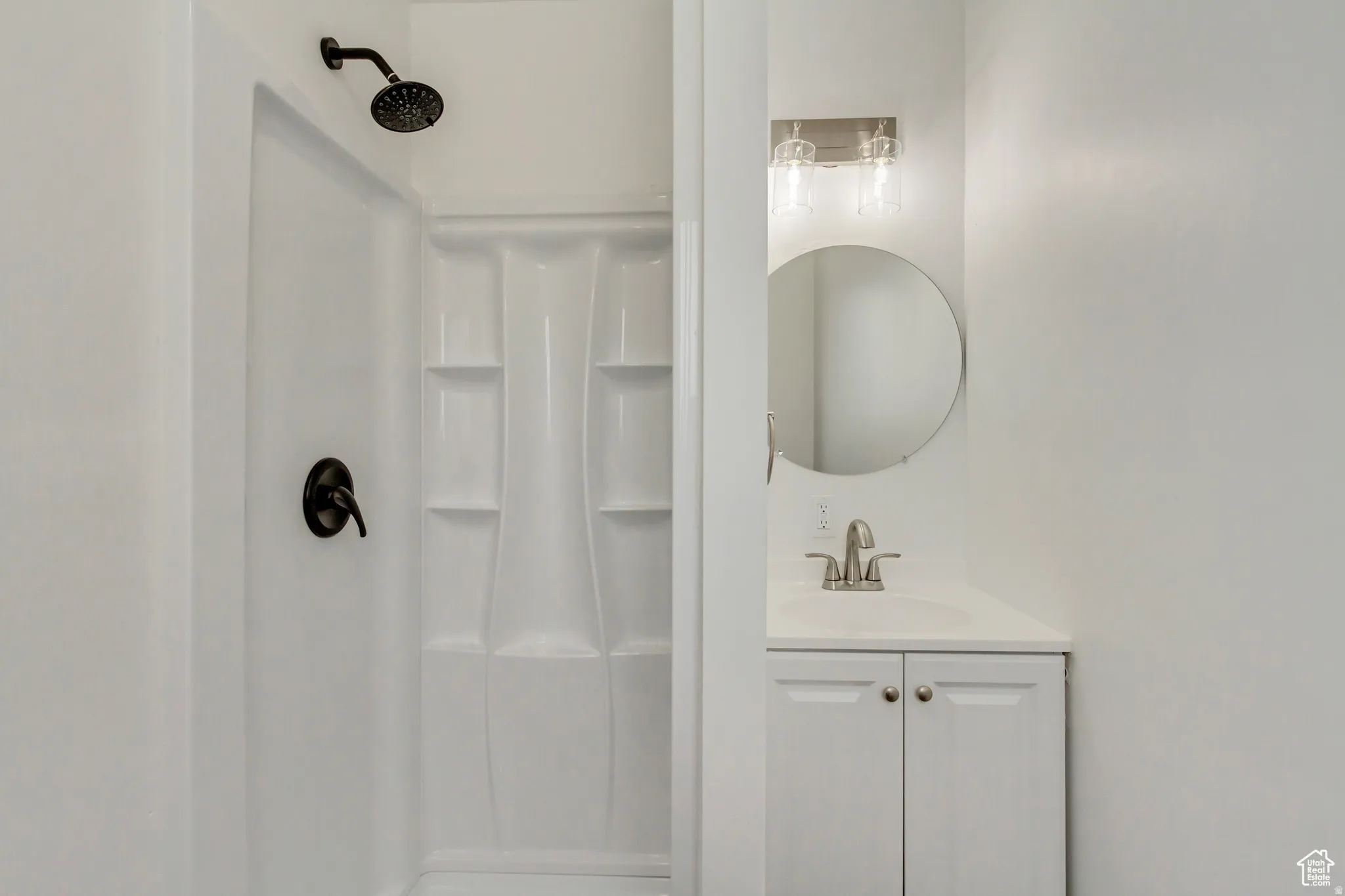 White shower enclosure with a black rain showerhead, coordinated black shower valve, and integrated shelving