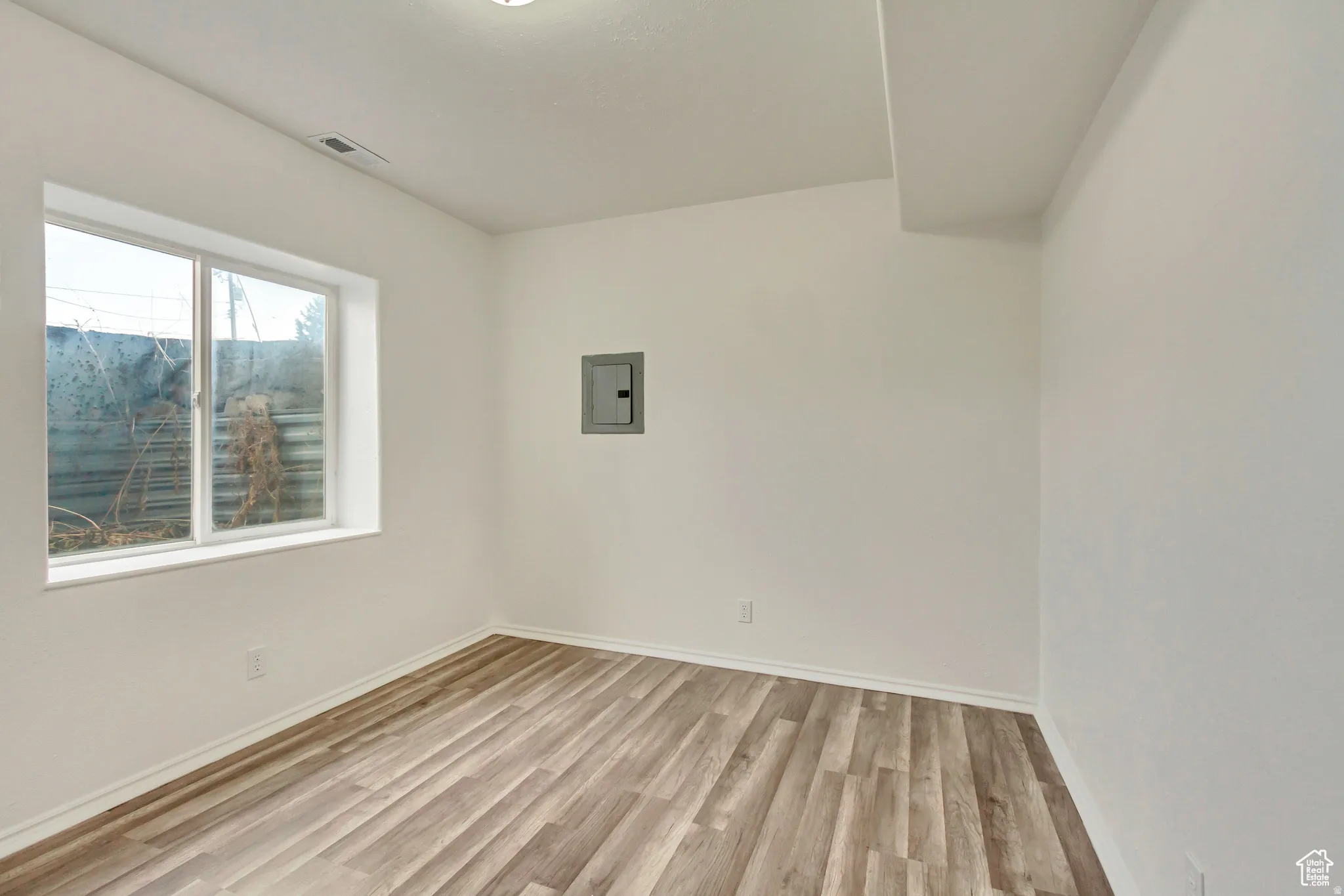 Room featuring wood-finish flooring, white baseboards, and a recessed ceiling light
