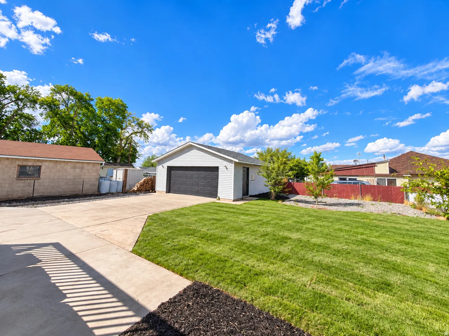 Attached two-car garage with a dark panel door, concrete driveway, and expansive lawn