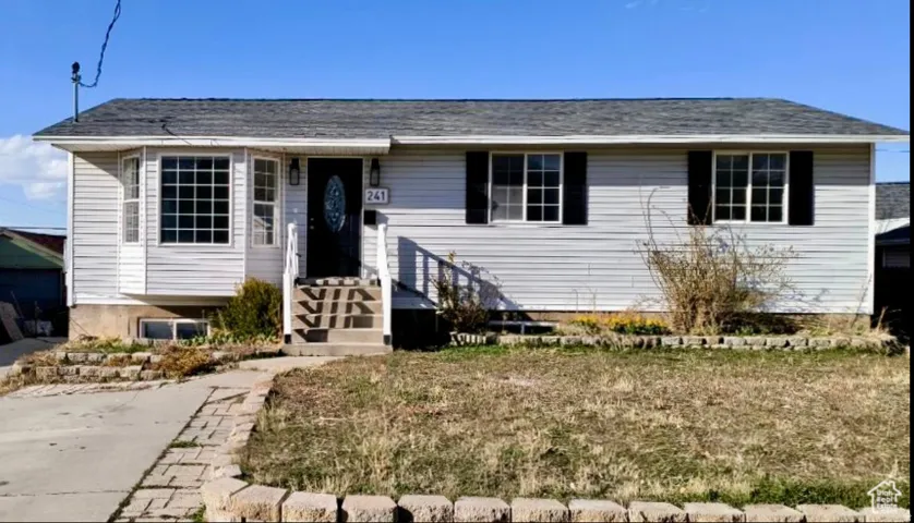 Charming single-story home featuring vinyl siding exterior, multi-pane windows with black shutters, and a covered front entry with railed steps