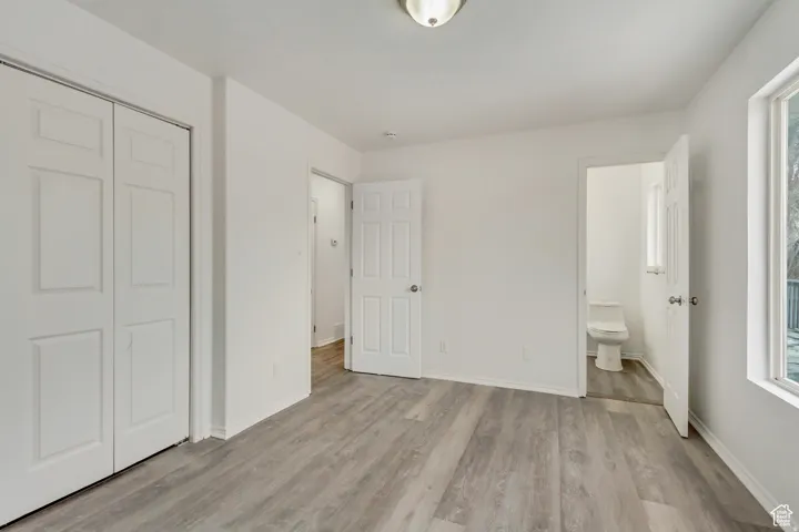 Spacious room featuring light-toned wood-finish flooring, white walls, and a ceiling-mounted light fixture