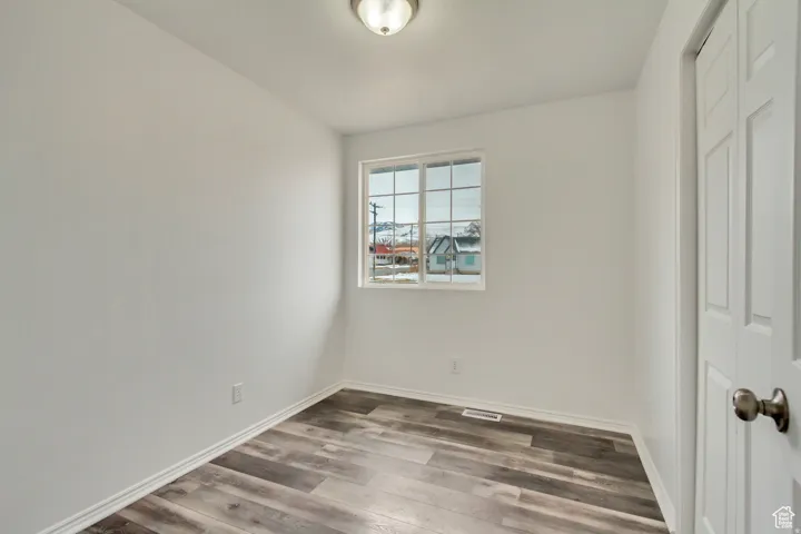 Room featuring wood-finish flooring, white walls, and a window with grid panes