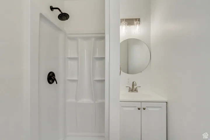 White shower enclosure with a black rain showerhead, coordinated black shower valve, and integrated shelving