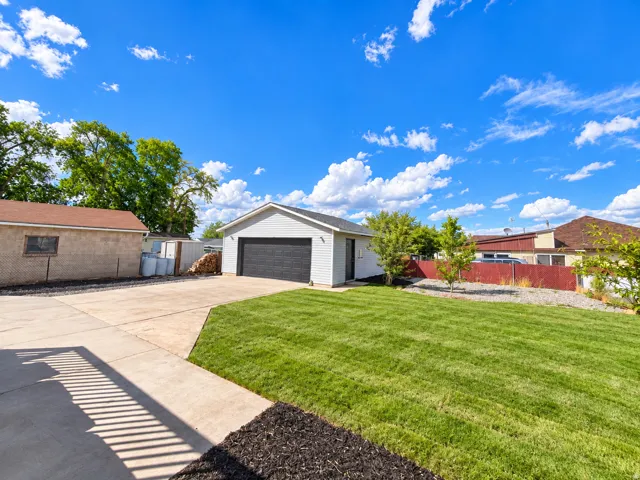 Attached two-car garage with a dark panel door, concrete driveway, and expansive lawn