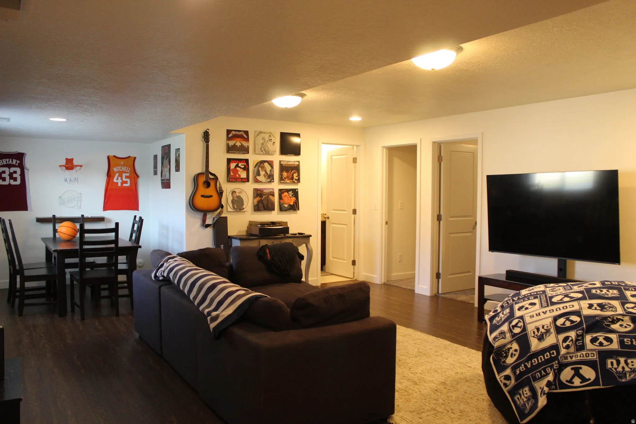 Brightly lit room featuring wood-finish flooring, white walls, and multiple panel doors