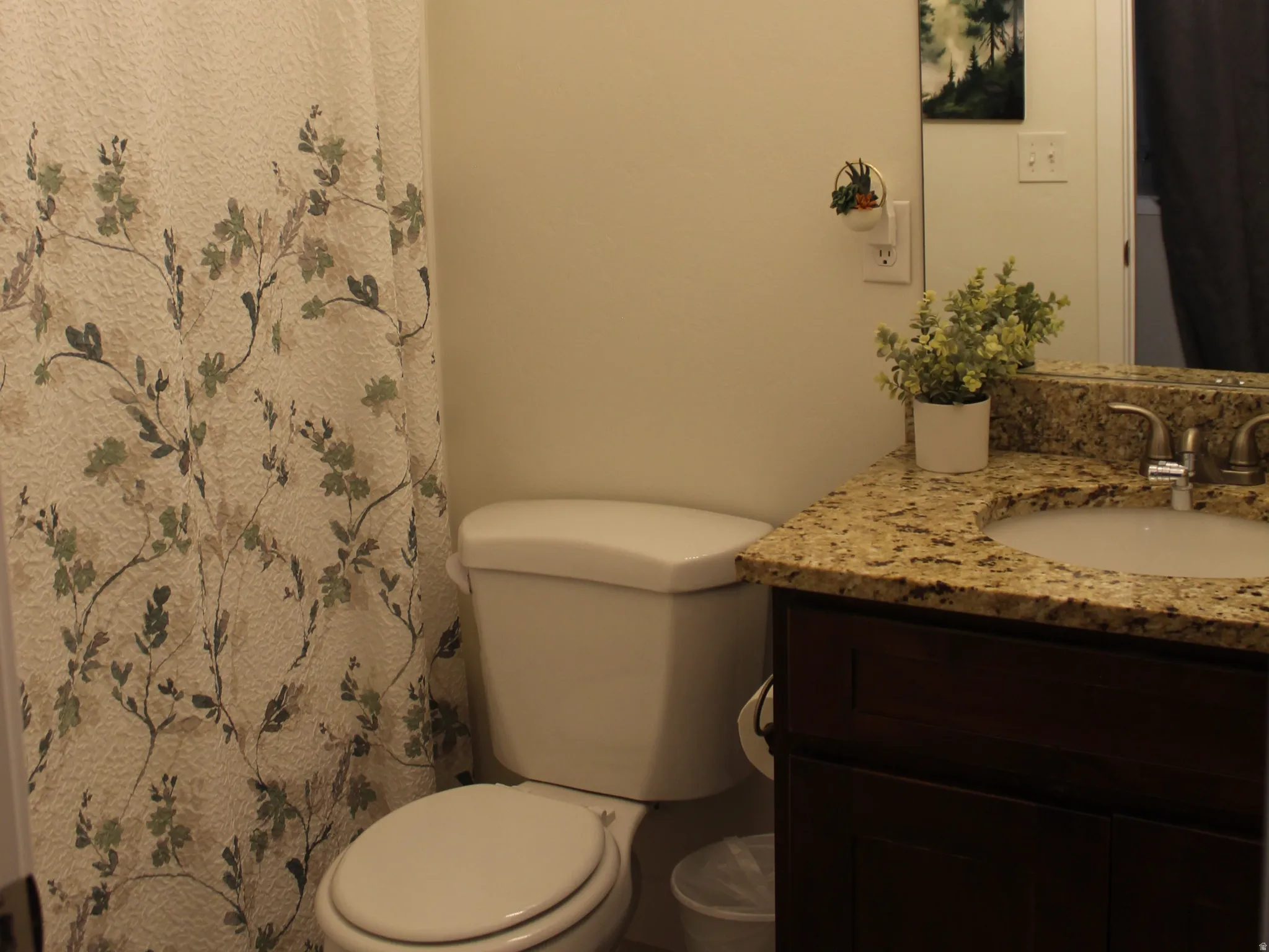 Vanity with granite-style countertop, undermount sink, and wood-finish cabinetry