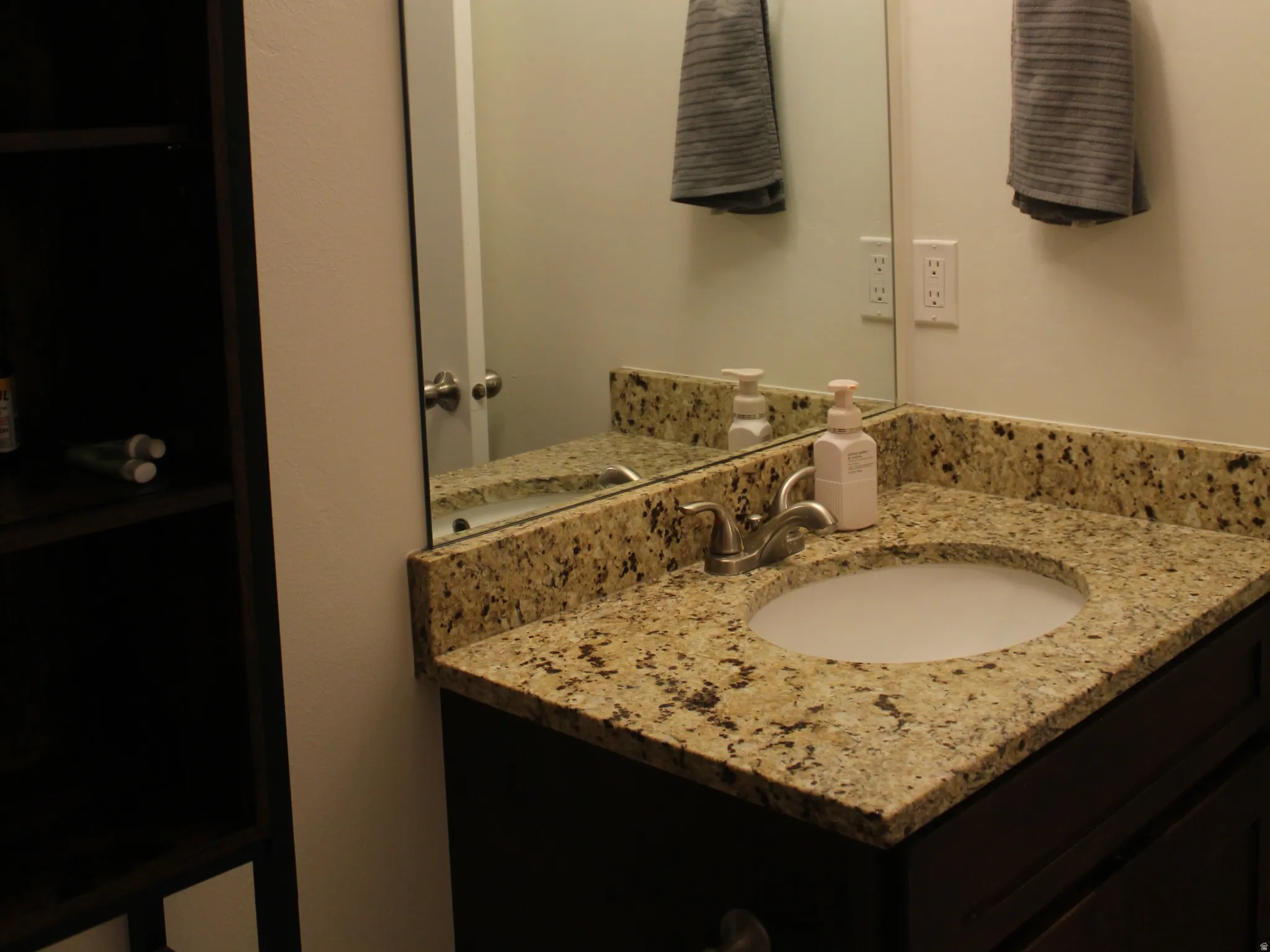 Bathroom vanity with a granite countertop, undermount sink, and a dark wood-finish cabinet