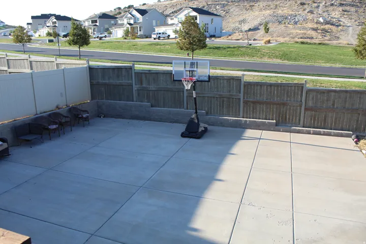 Expansive concrete patio area with varied fencing and a retaining wall
