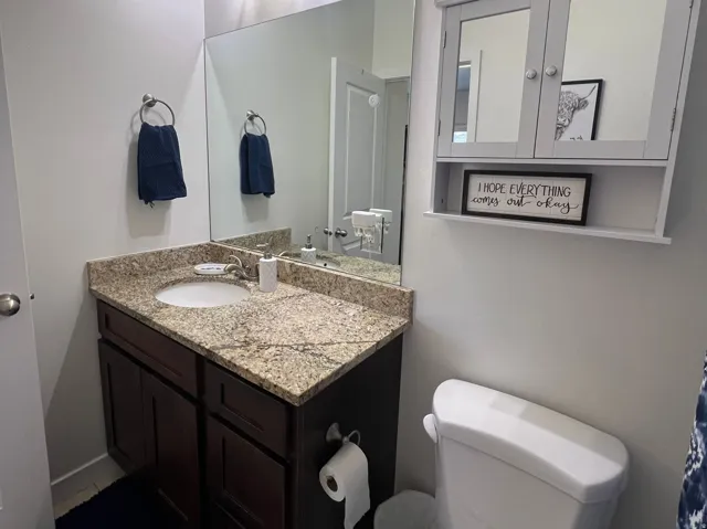 Vanity with a granite countertop, undermount sink, dark wood-finish cabinetry, and a mirrored medicine cabinet
