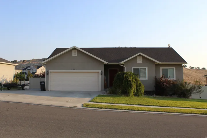 Single-story residence featuring a two-car garage, stucco exterior, and a dark shingle roof