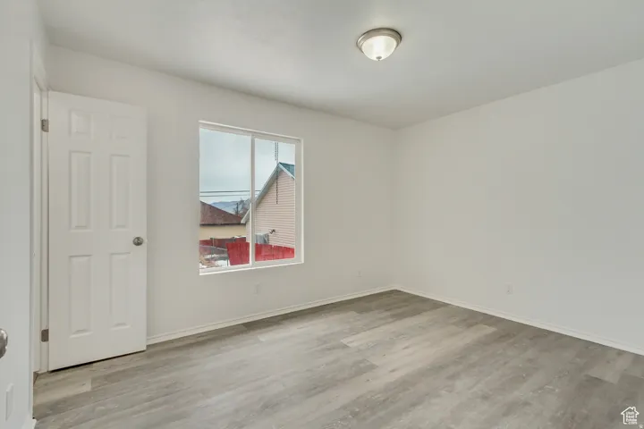 Room featuring light gray wood-finish flooring, white painted walls, and a window with white trim