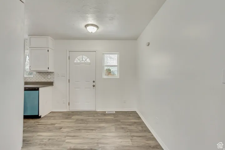 Open concept living area featuring wood-finish flooring and a white entry door with an arched window