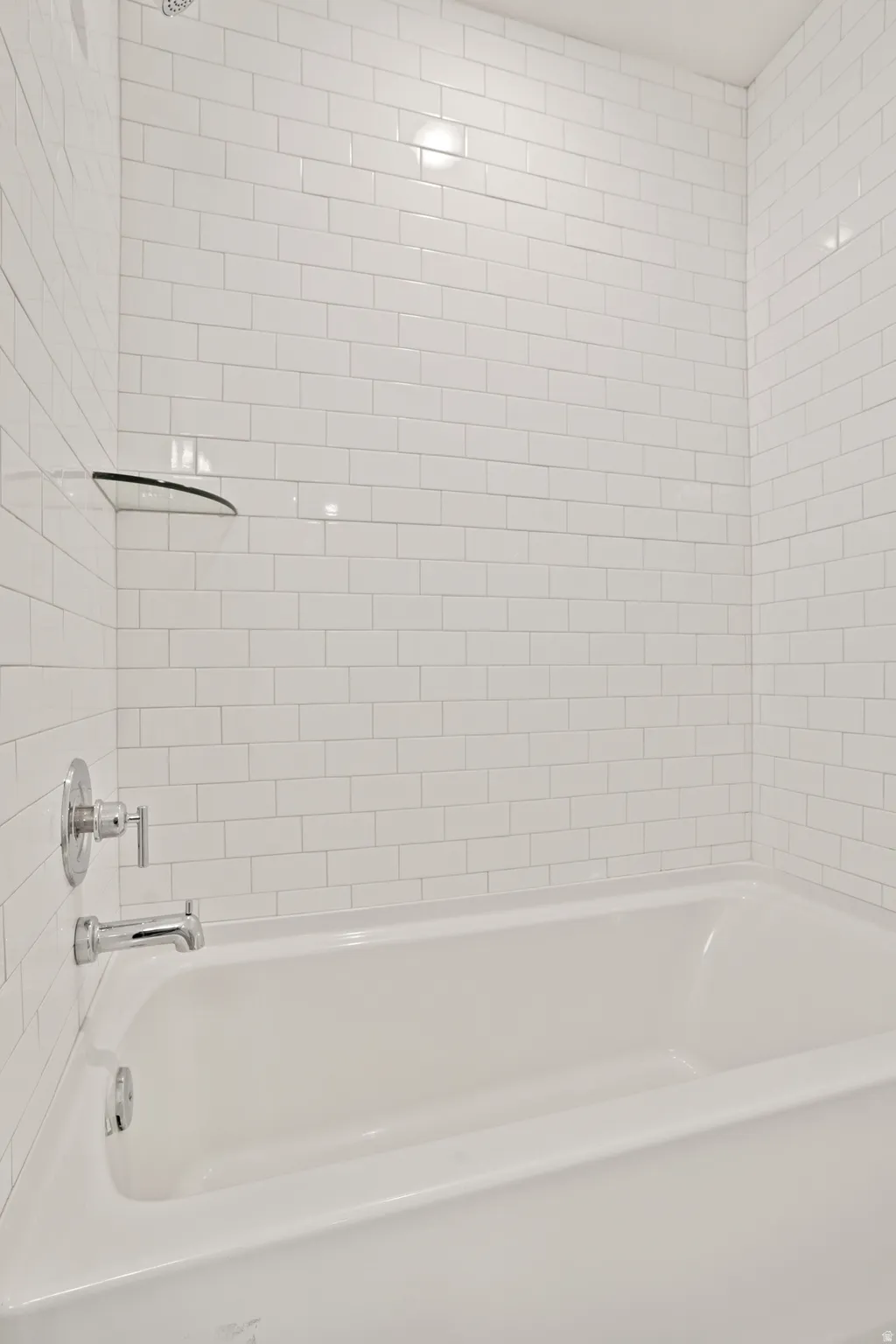 White subway tile surround with chrome fixtures and a built-in tub