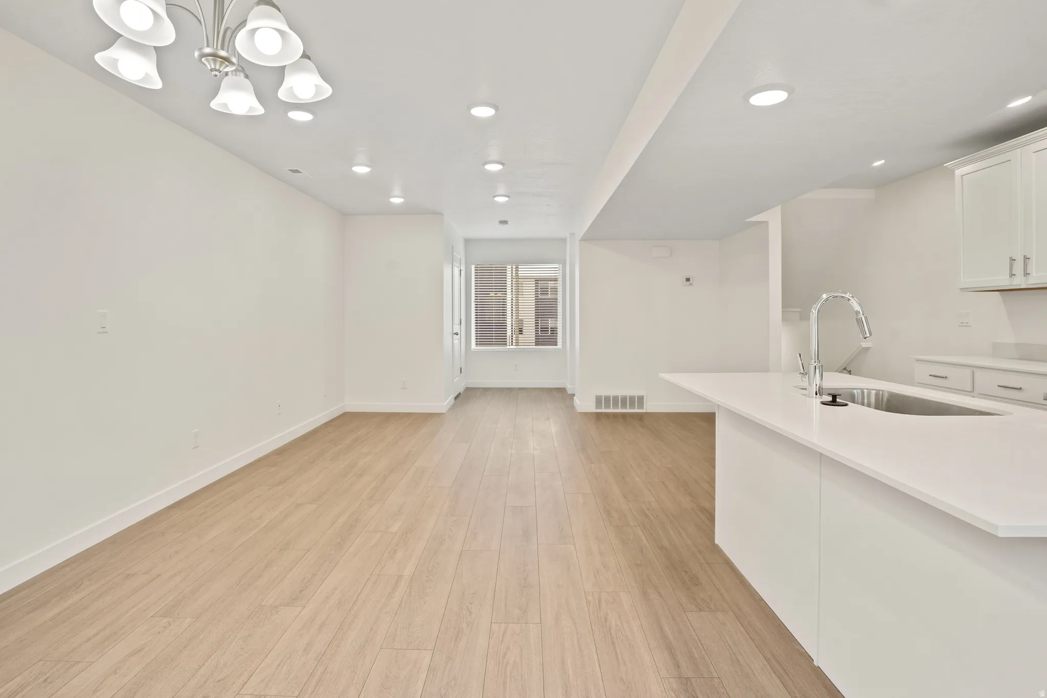 Open-concept living area featuring light wood-finish flooring, white walls, and recessed lighting