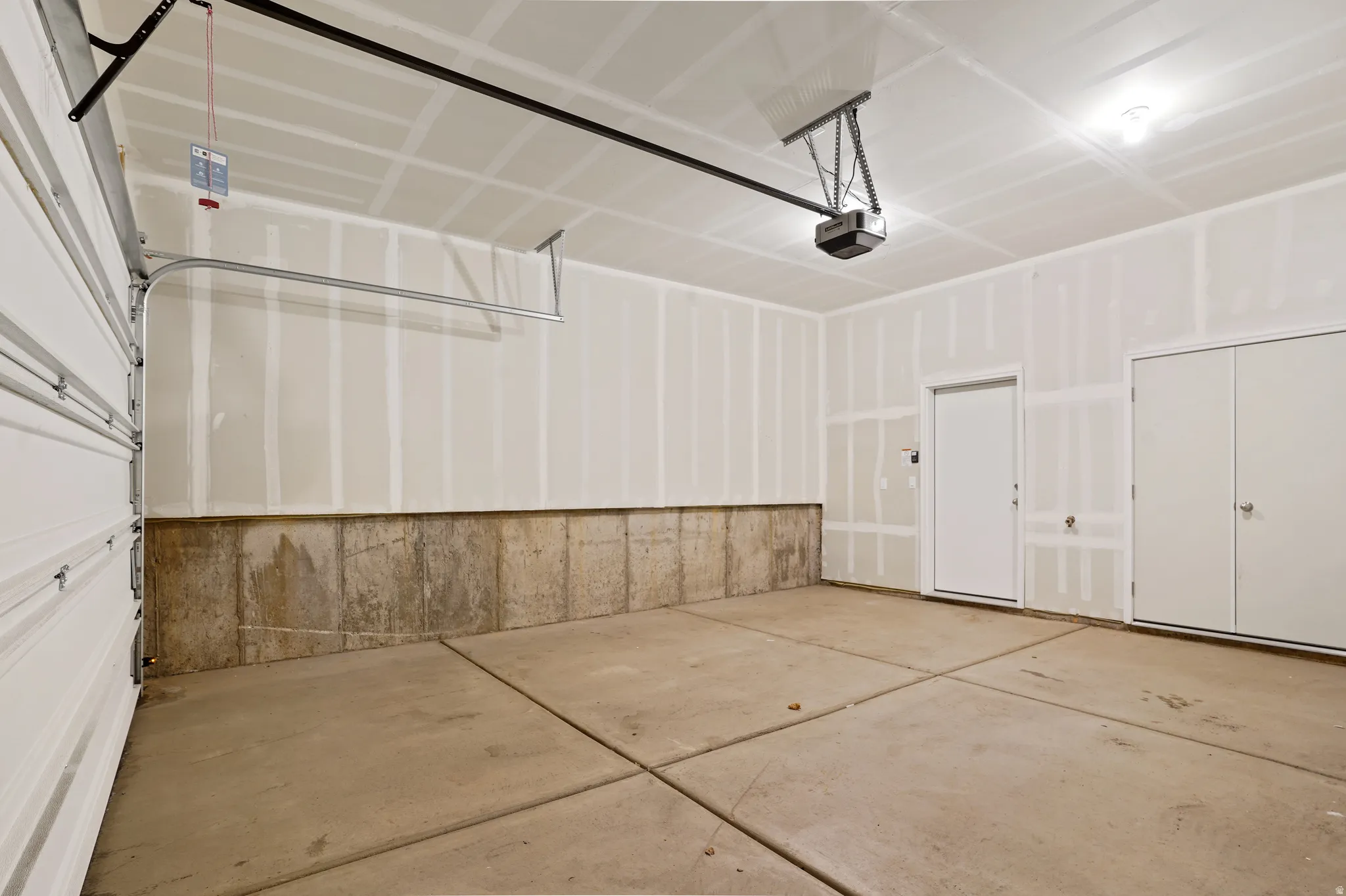 Attached garage featuring a concrete floor, automatic garage door opener, interior access door.