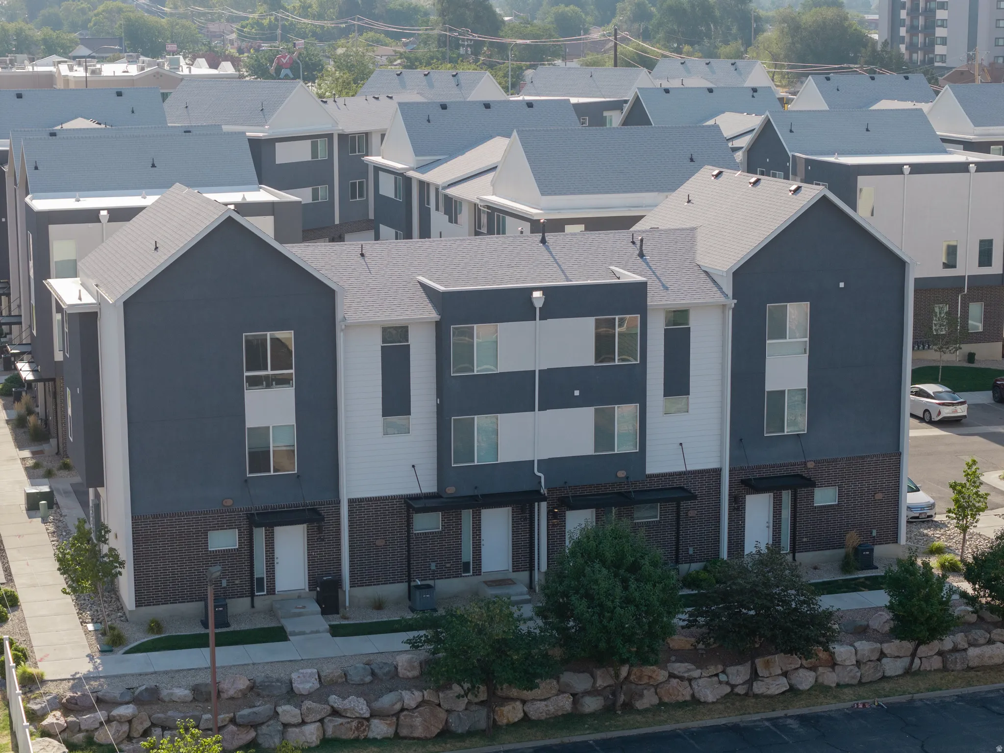 Modern townhome exteriors featuring multi-toned siding, gabled rooflines, and a brick lower facade