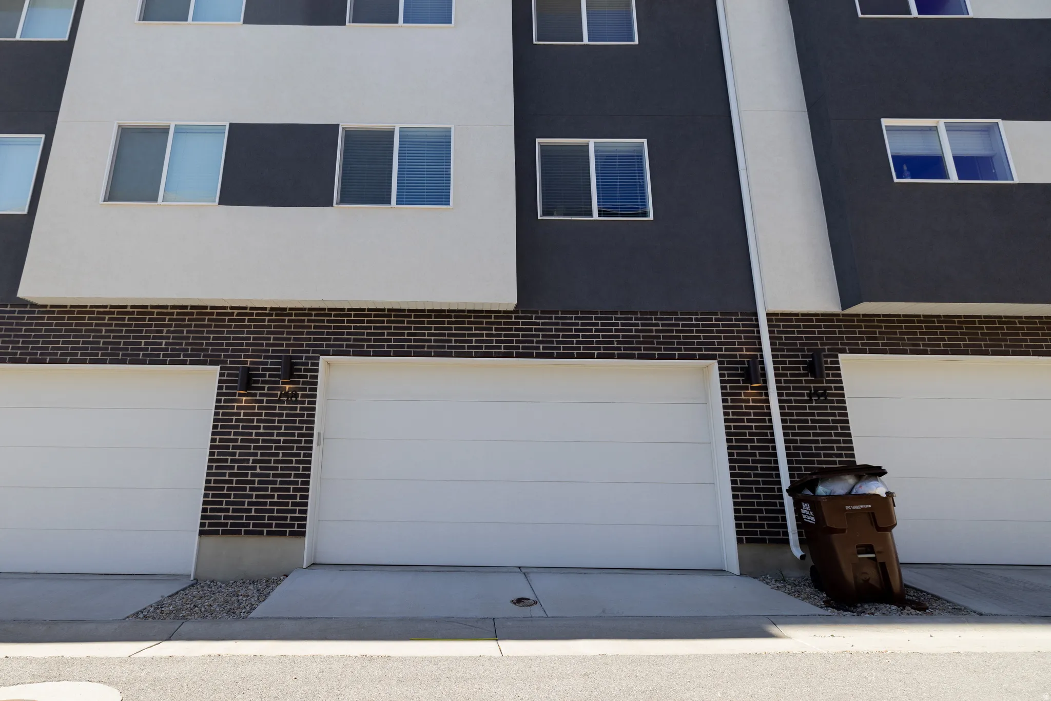 Modern facade featuring white and charcoal paneling, black brick accents, and multiple windows