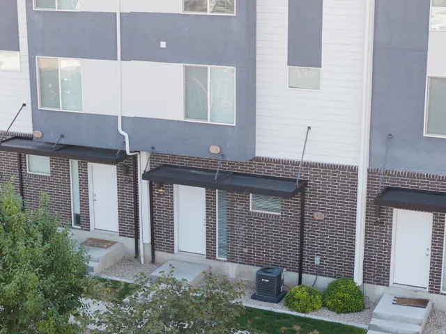 Contemporary townhome exterior featuring a combination of gray stucco, white siding, and brick accents