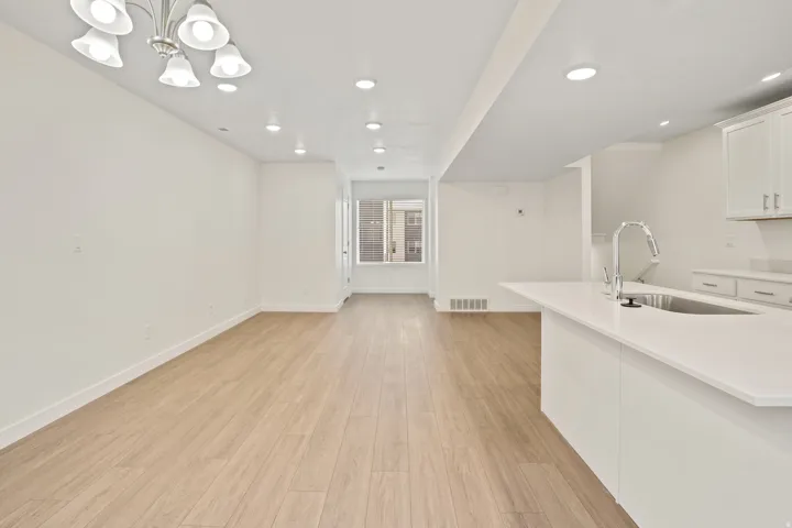 Open-concept living area featuring light wood-finish flooring, white walls, and recessed lighting