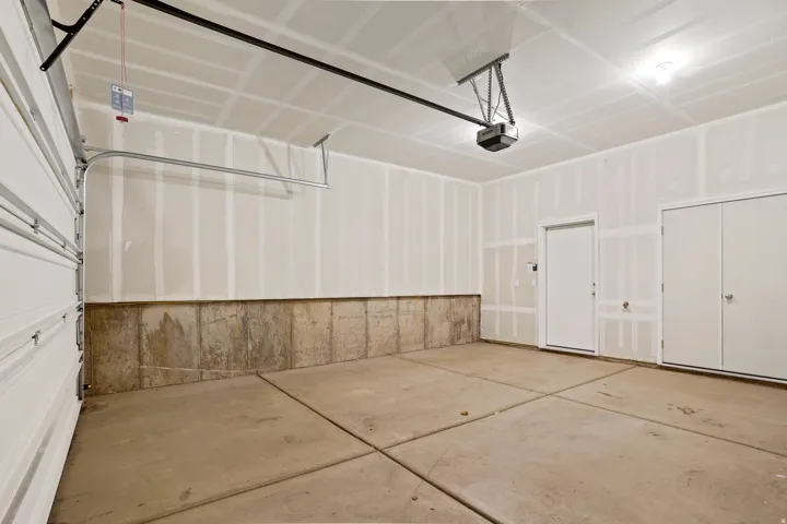 Attached garage featuring a concrete floor, automatic garage door opener, interior access door.