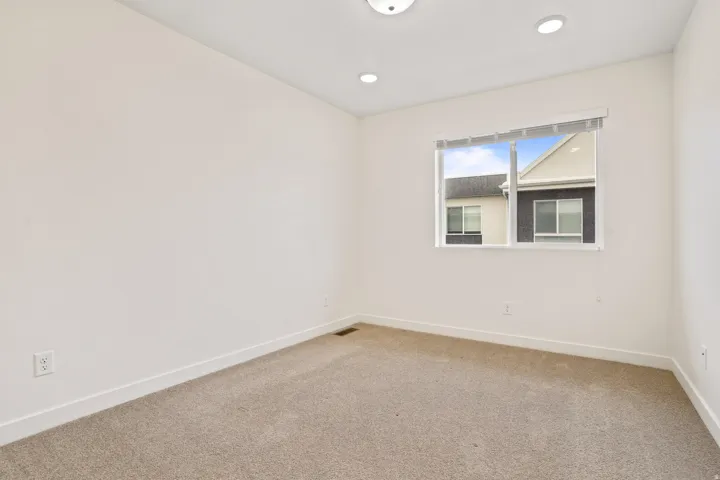 Room with neutral wall paint, light carpet flooring, and a single window with blinds