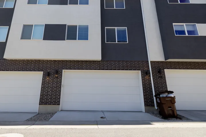 Modern facade featuring white and charcoal paneling, black brick accents, and multiple windows