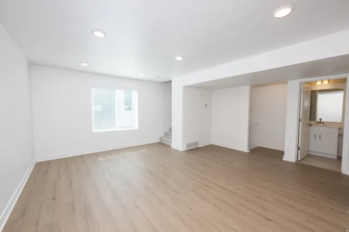 Spacious interior featuring wood-finish flooring, recessed lighting, and a bright window with blinds
