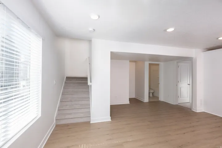Spacious room featuring wood-finish flooring, white baseboards, and bright recessed lighting