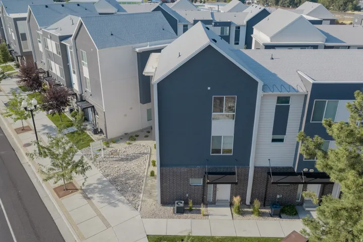 Contemporary townhome featuring blue and white siding, dark brick accents, and a grey shingle roof