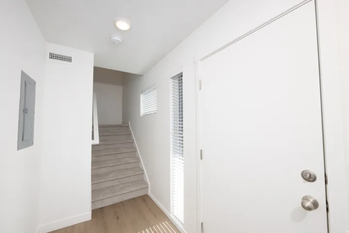 Entryway featuring a white door with brushed nickel hardware, wood-finish flooring, a carpeted staircase, and a recessed ceiling light