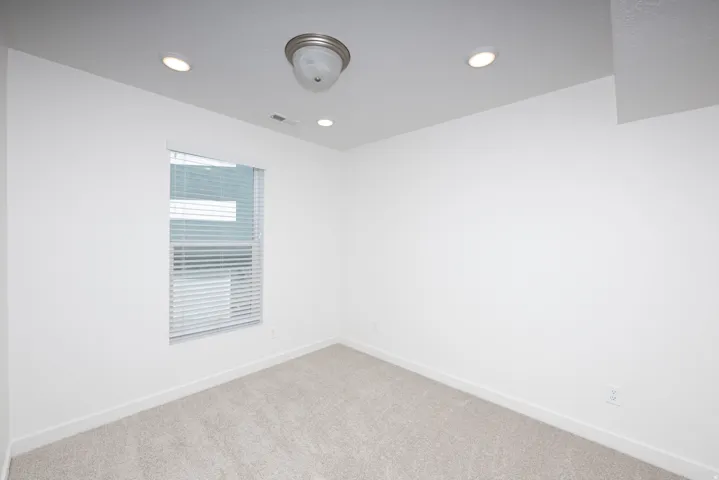 Room featuring a window with horizontal blinds, neutral carpet, white baseboards, and white walls