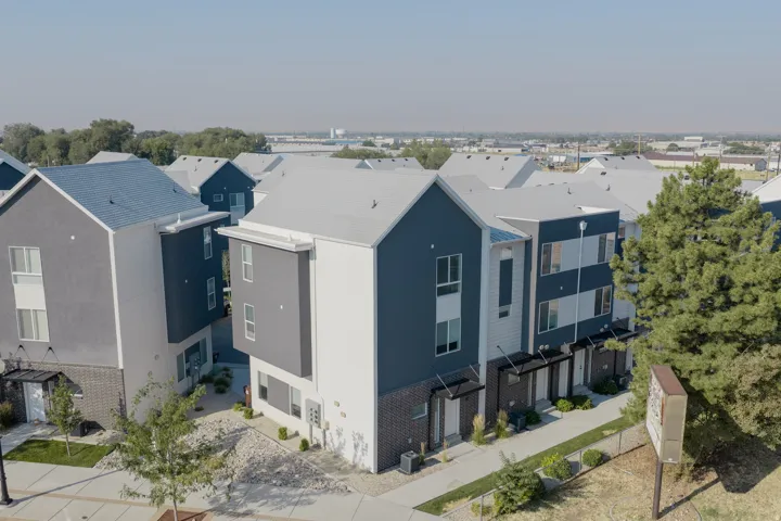 Modern multi-story residential buildings featuring a striking combination of dark grey and white siding, light grey roofs, and a low-maintenance landscape design