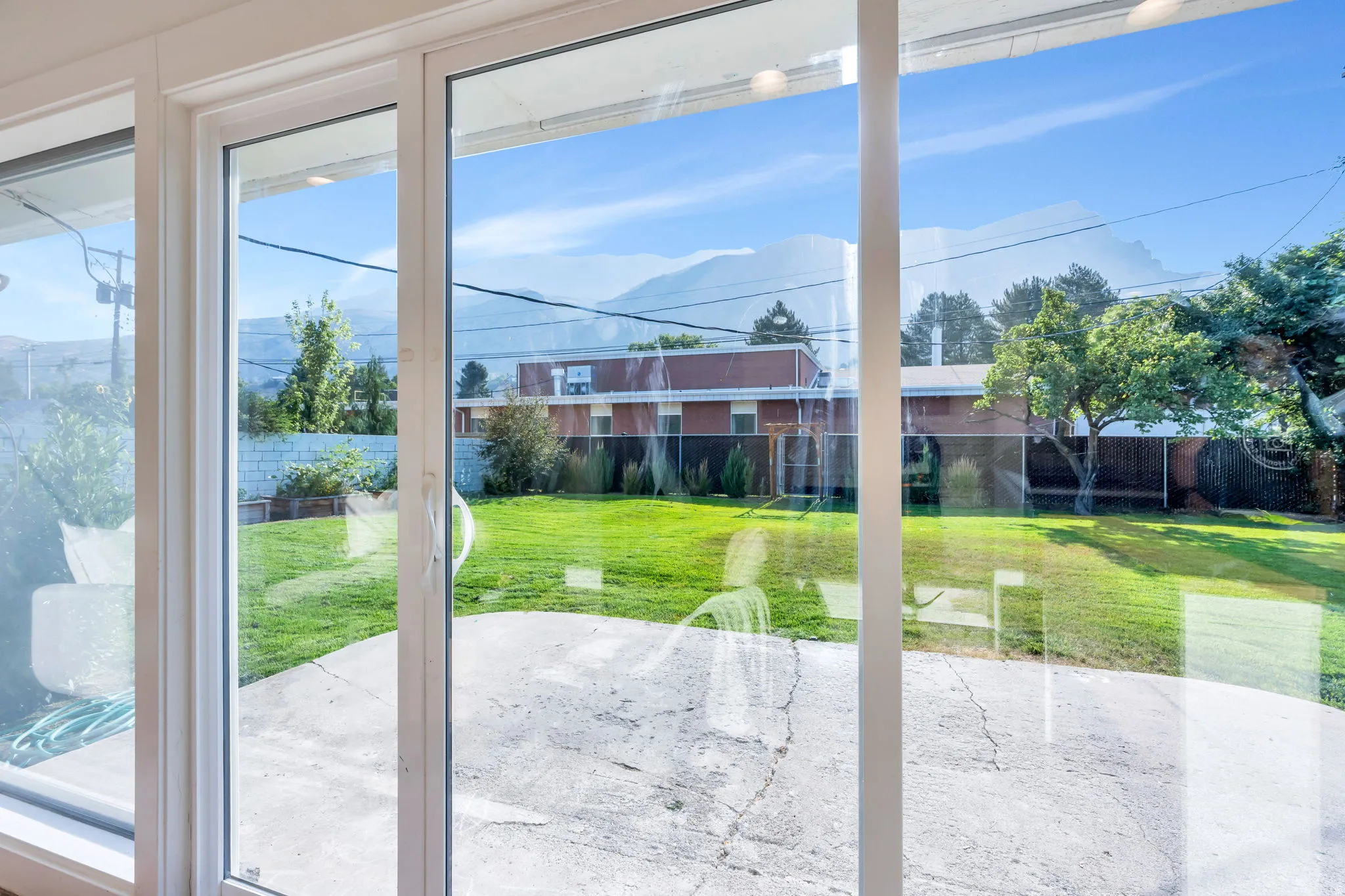 Sliding glass doors opening to a concrete patio and a large grassy yard