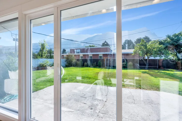 Sliding glass doors opening to a concrete patio and a large grassy yard